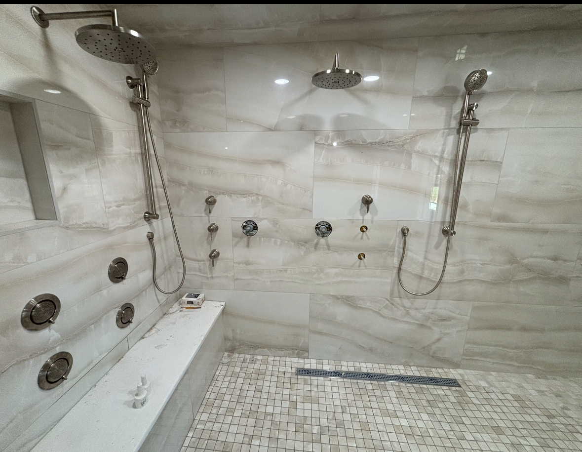Luxury walk-in shower with multiple heads and marble slab tile